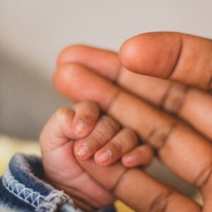 Relationship challenges after the birth of a baby A photo of a baby's hand, grasping a parent's finger.