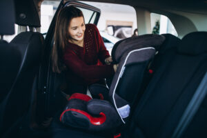 Smiling woman securing baby car seat, demonstrating car restraint safety for babies.
